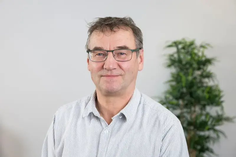 Ronny Strehlow mit Brille und gestreiftem Hemd, schaut freundlich in die Kamera.